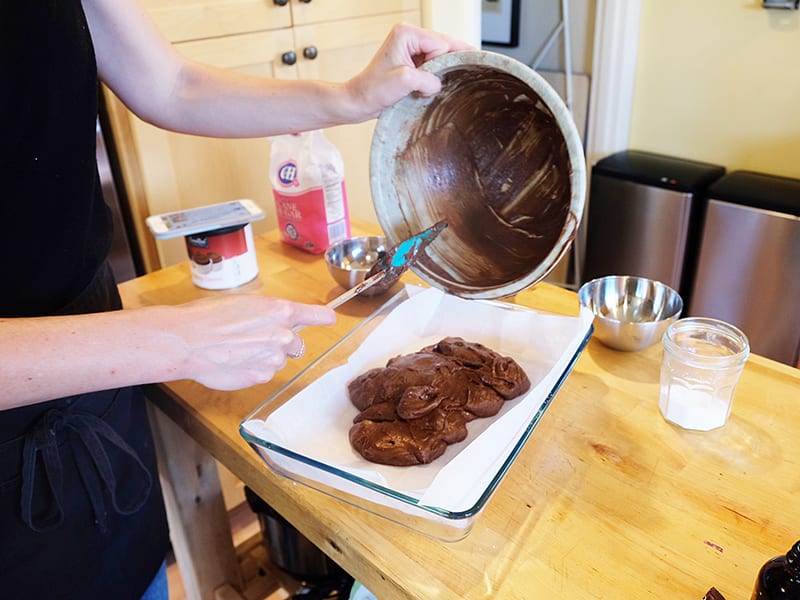 person emptying brown batter onto a glass dish | Dockside Cannabis