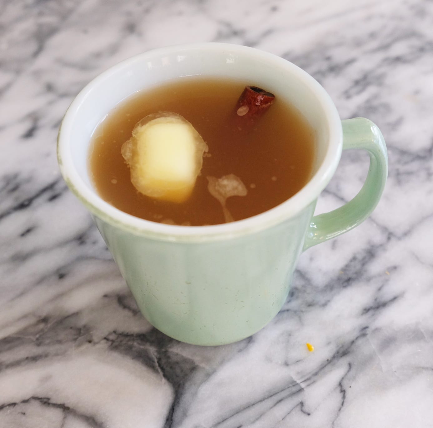 cup filled with cider with apple chunk and cinnamon in it | Dockside Cannabis