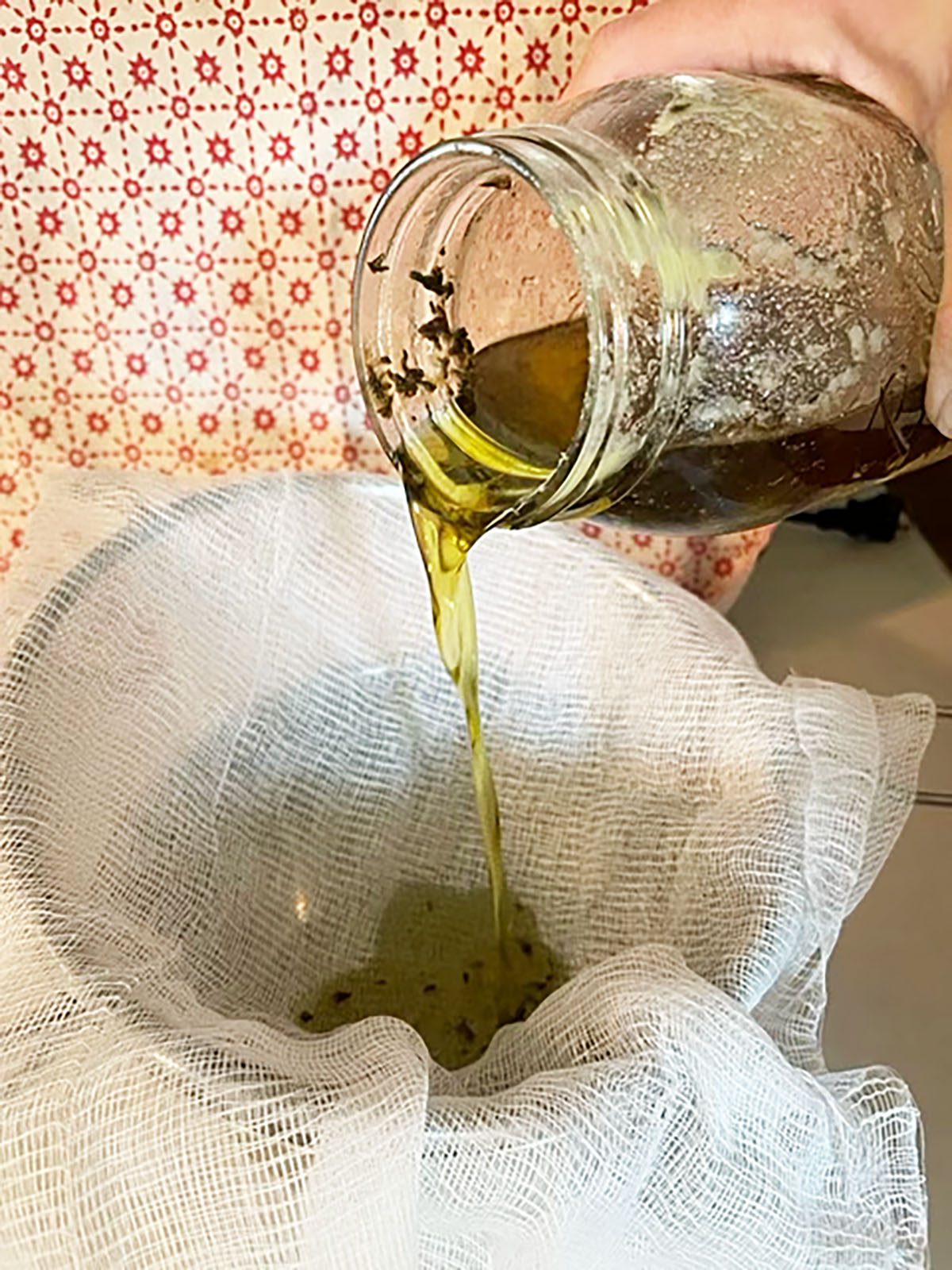 liquid cannabutter being poured through cheesecloth into a bowl to separate the oil from the plant matter.
